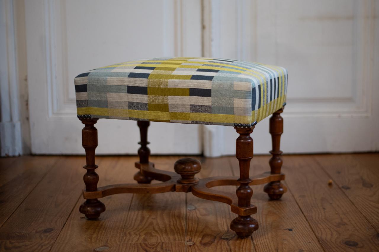 Tabouret rectangulaire refait totalement recouvert d'un tissu à 
            rayures blanc, vert et bleu pâle. Finition clous